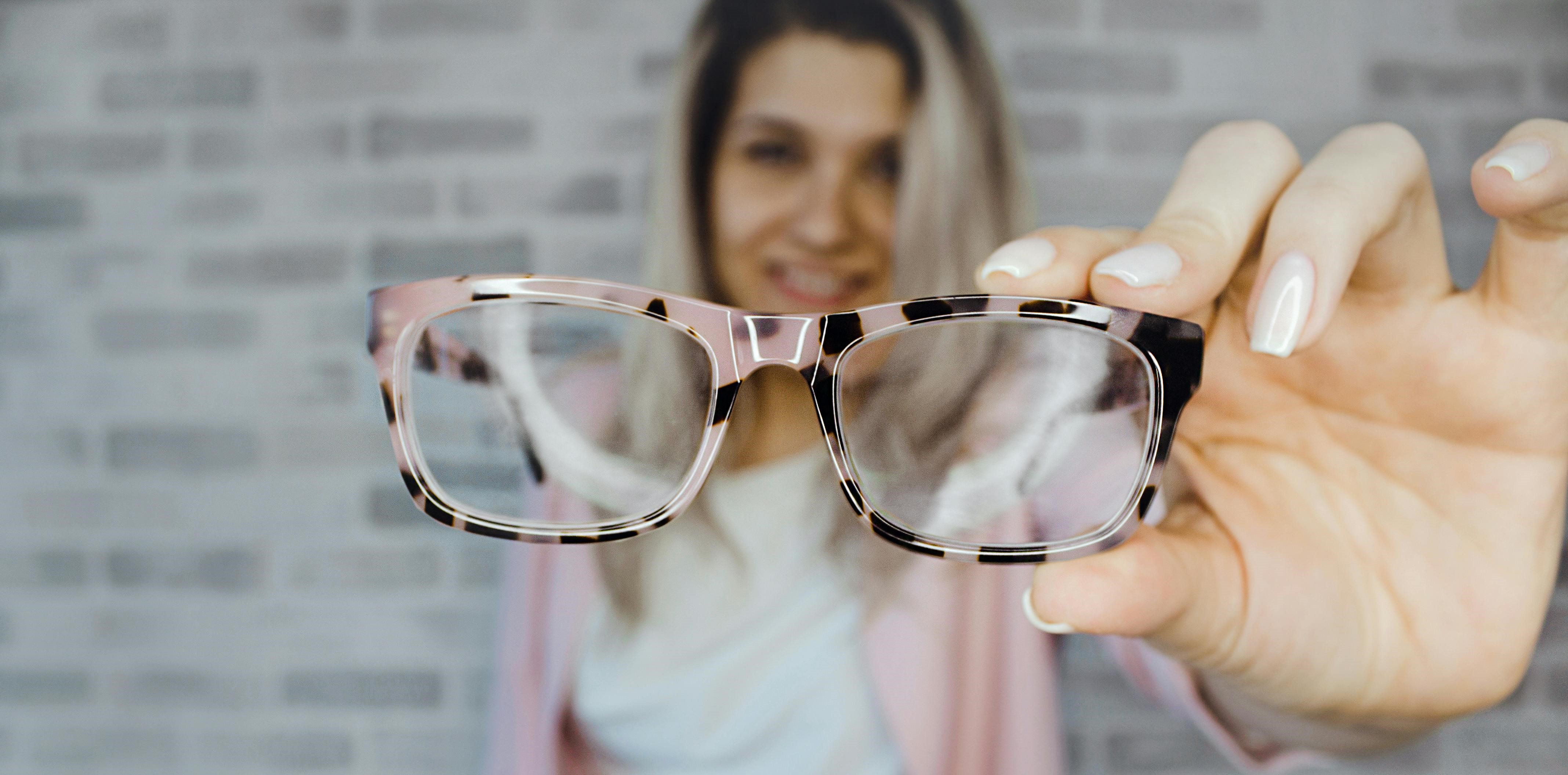 Img of person holding out glasses for you to try on